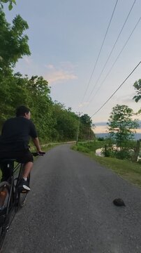 Cyclist Riding on Country Road at Sunset