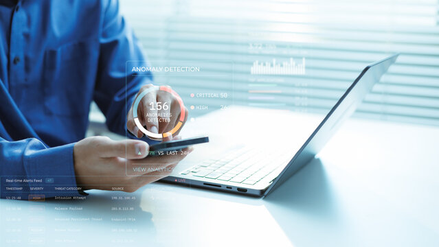 Cybersecurity analyst reviews anomaly detection and real-time threat alerts on a laptop and smartphone. The scene represents network risk, malware detection, incident response and SOC monitoring.