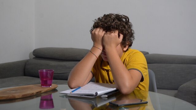 12 year old boy child suffering from a migraine headache &ndash; student experiencing head pain and fatigue stress from homework and studying -  Fever, illness, and medical care in childhood