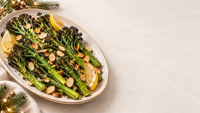 Roasted broccolini with toasted almonds and lemon on a cream table