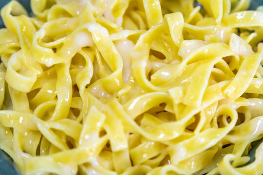 Traditional fettuccine Alfredo &mdash; fresh egg fettuccine pasta coated in a creamy butter and parmesan cheese sauce, served on a green ceramic plate with a fork.