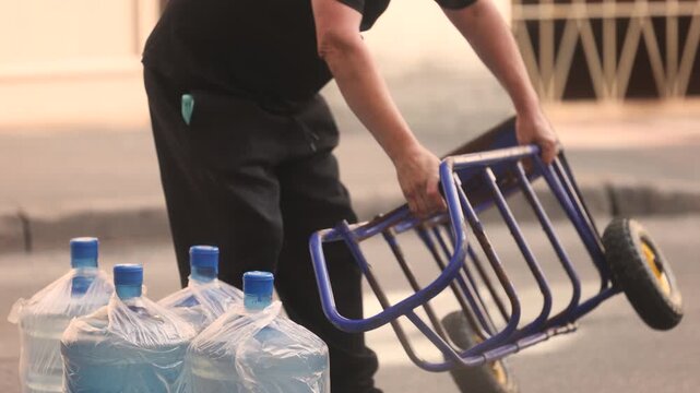 Delivery worker loads large water bottles onto a cart for office supply