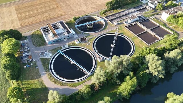 Aerial view of waste treatment plant with circular sedimentation tanks and rectangular basins near the river in Tubingen, Baden-Wurttemberg, Germany.