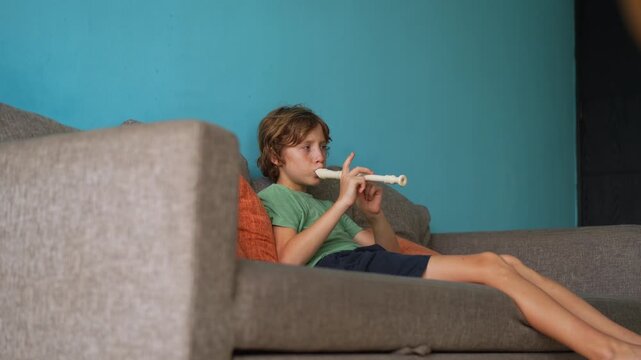 A little boy learns to play the flute at home, practicing with focus and enthusiasm in a cozy, warm setting. A charming scene of early musical exploration, creativity, and childhood growth.