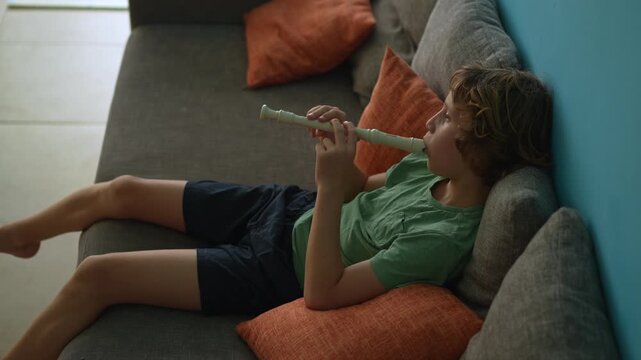 A little boy learns to play the flute at home, practicing with focus and enthusiasm in a cozy, warm setting. A charming scene of early musical exploration, creativity, and childhood growth.