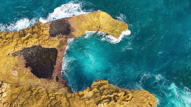 Waves crashing into rocky cove at Devils Tears on Nusa Lembongan, turquoise water swirling inside natural coastal rock formation in Bali, Indonesia