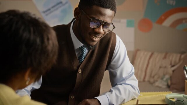 African American male tutor explaining lesson to African American teenager writing notes. Tilt down shot suitable for educational marketing and private tutoring campaigns