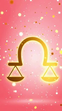 Vertical video of glowing golden libra scale zodiac sign outline shining and zooming in with falling sparkling glitter particles on pink background