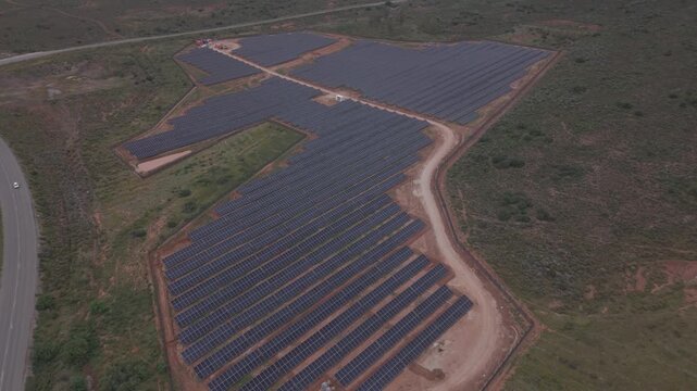 Aerial view of a large solar farm with rows of photovoltaic panels situated in the rural landscape near Bonnievale, Western Cape, South Africa.