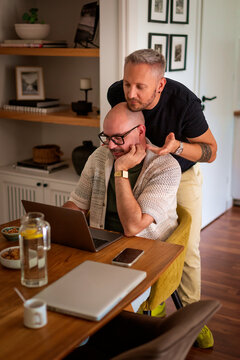 Male partners doing paperwork and online banking together in their living room