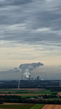 Aerial view of Tagebau Hambach power plant with wind turbines and agricultural fields under a cloudy sky in Elsdorf, Nordrhein-Westfalen, Germany.