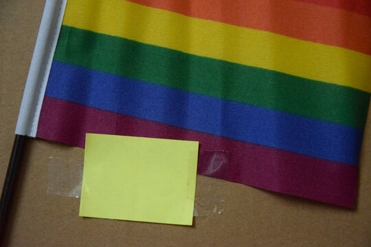 Rainbow Pride Flag with Green Note on Brown Cardboard Background