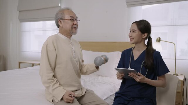 Professional Asian woman nurse physiotherapist using a dumbbell for workout exercise for physical recovery of muscles and bones of a senior man patient in hospital bed. Healthcare and medical concept.