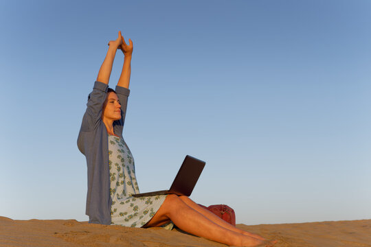 Woman stretching arms during remote work break outdoors