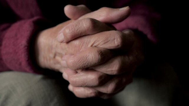 Close up senior person arthritic and wrinkled hands clasped together, slowly opening to reveal empty palms, symbolizing hope, vulnerability and passage of time. Old person suffering from hand tremors