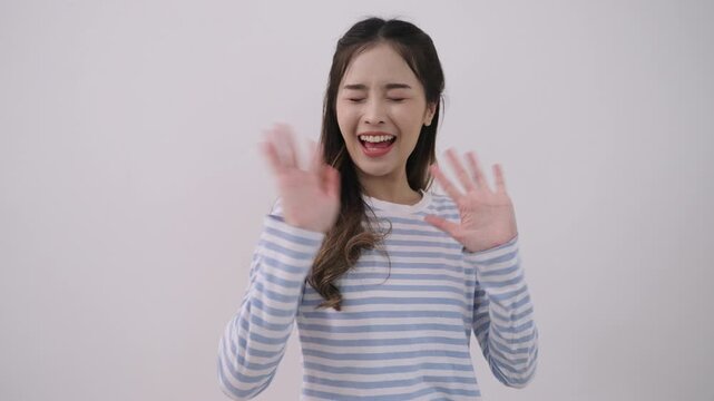 Happy beautiful young Asian woman standing smiling, arms crossed while waving and blow a kiss with her hands with fun and cheerful against white studio background. Positive confidence of female. 