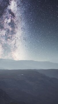 Stars fill the night sky above dark mountain silhouettes. The view shows sparkling light scattered across the horizon. The scene captures the beauty of nature at night with no signs of clouds.