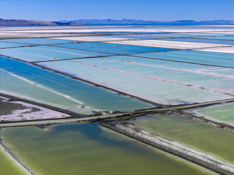 Aerial view of Great Salt Lake solar evaporation ponds with vibrant colors from microorganisms and geometric dikes in Ogden, Utah, United States.