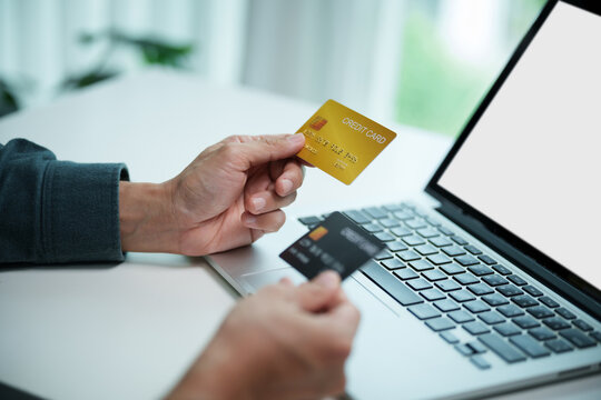 Person holds credit cards beside a laptop for online payment, highlighting digital shopping, cashless transactions, banking and financial convenience.