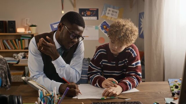 African American tutor explaining school assignment to Caucasian teenager at desk. Clip works well for private tutoring services, academic mentoring, and education marketing