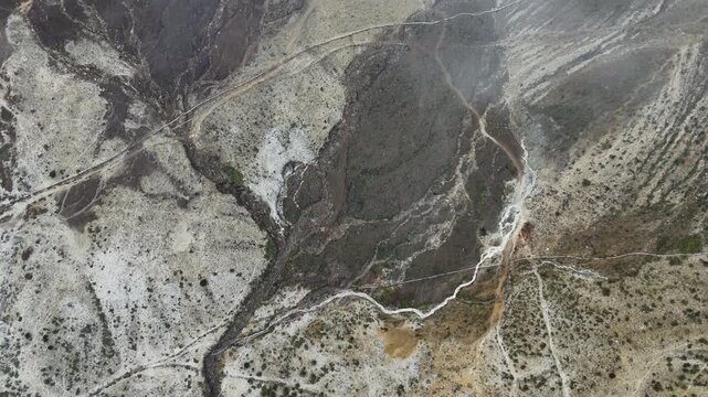 Aerial view of the rugged volcanic terrain of Mount Papandayan with sulfurous deposits, winding streams, and patches of green vegetation in Garut, West Java, Indonesia.