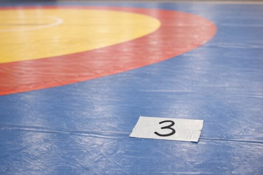 A wrestler lying down on a wrestling mat, ready to start a match