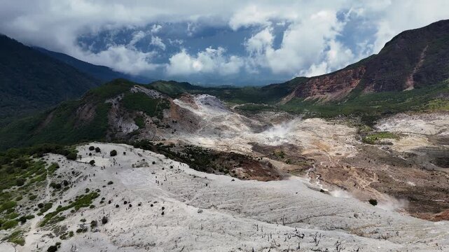 Aerial view of the volcanic crater of Mount Papandayan with sulfur deposits and rocky terrain under a cloudy sky in Garut, West Java, Indonesia.