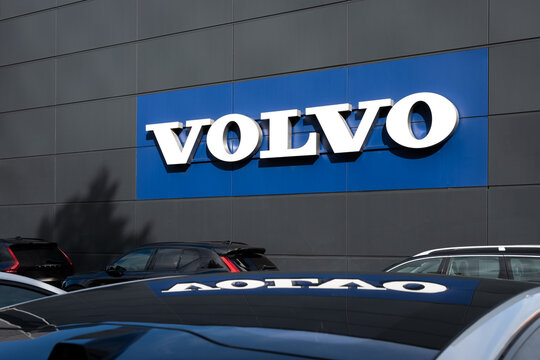 Logo of a Volvo car dealership with cars parked in front