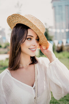 Smiling young woman in a straw hat enjoying a sunny summer day outdoors, casual boho portrait with white blouse and natural makeup