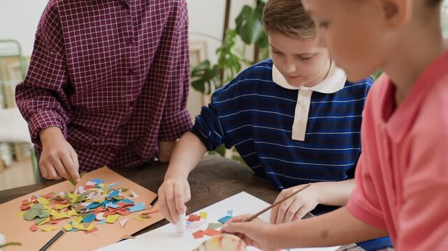 Children creating paper collage in craft masterclass with tilt up. Visual is suitable for promoting art school programs and workshops