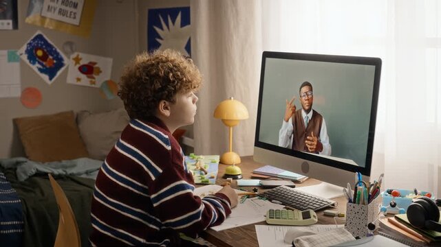 Caucasian teenage boy attending online class with African American tutor on computer monitor. Clip suitable for edtech campaigns, remote tutoring platforms and distance learning advertising