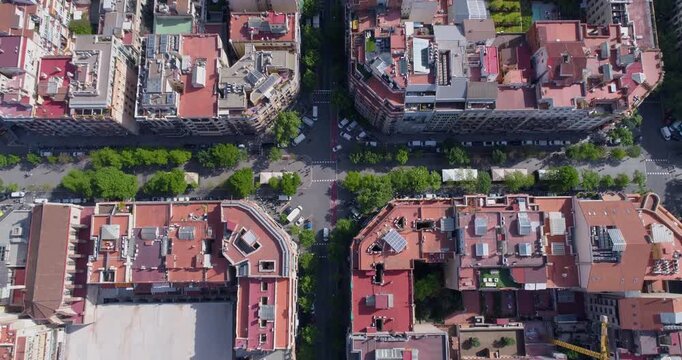 Aerial view of the Eixample district in Barcelona, featuring its iconic grid layout, historic buildings with red rooftops, and busy city streets in Barcelona, Catalonia, Spain.