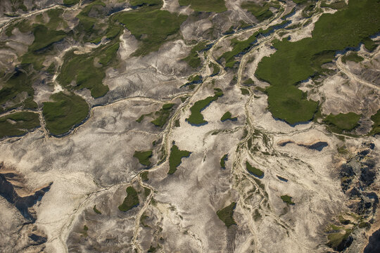Aerial view of the rugged landscape of Badlands National Park with eroded rock formations, deep gullies, and patches of green vegetation in Interior, South Dakota, United States.
