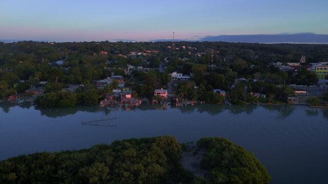 Coastal village sunset aerial view flying over lagoon toward Pueblo Viejo with sunlight illuminating houses traditional wooden fishing huts and moored boats near Tampico Veracruz Mexico