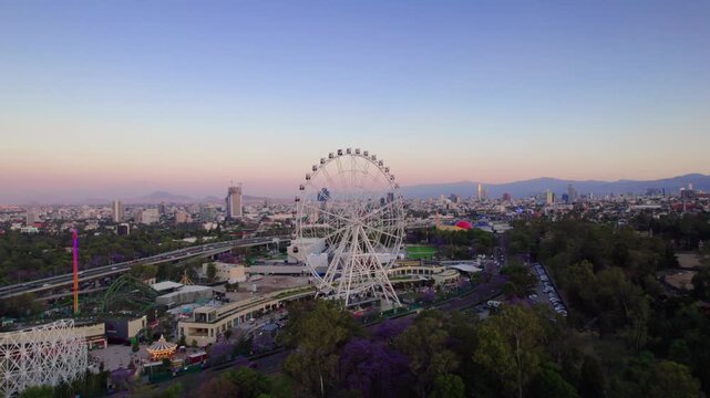 Aerial view of the Ferris wheel in Bosque de Chapultepec at sunset with the Mexico City skyline in the background, Mexico City, Mexico City, Mexico.