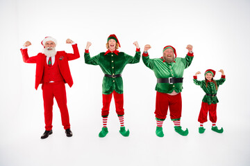 Fototapeta premium Santa and three joyful elves flexing together for a festive family Christmas celebration in holiday costumes