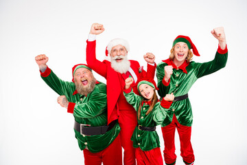 Fototapeta premium Santa Claus and joyful elves celebrating together in festive red and green holiday costumes, smiling family group cheering with raised fists for Christmas celebration