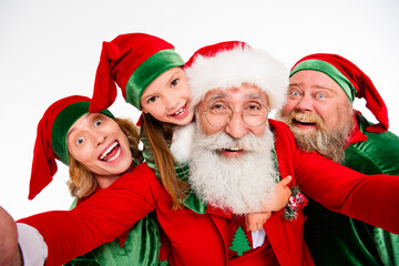 Fototapeta premium Santa Claus and happy elves taking a festive family selfie together, laughing and celebrating Christmas spirit with joy and holiday costumes