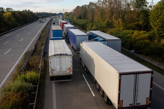 Scenic view queue of trucks european highway traffic jam at sunset sunrise autumn day. Freight congestion accident delays, border disruption transport pressure Europe. Cargo lorry semi-trailers stuck