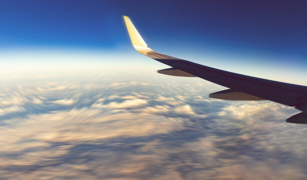  Ala de avi&oacute;n volando alto sobre nubes esponjosas durante el atardecer. Viaje de vuelo comercial, viaje de aventura, libertad, transporte global, vista a gran altitud.