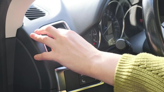 Car ventilation setup as hand changes dashboard air vent direction, adjusting louvers beside climate controls for airflow inside cabin and changing outlet direction for circulation through vehicle