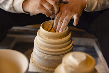 Potter shaping handmade clay vessel on wheel in ceramic workshop © MaiVan