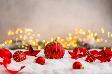 Fototapeta premium A Christmas background featuring red baubles with golden glitter stripes, a star, and ribbon framing wide snowy ground, softly lit by warm twinkling lights with generous copy space.