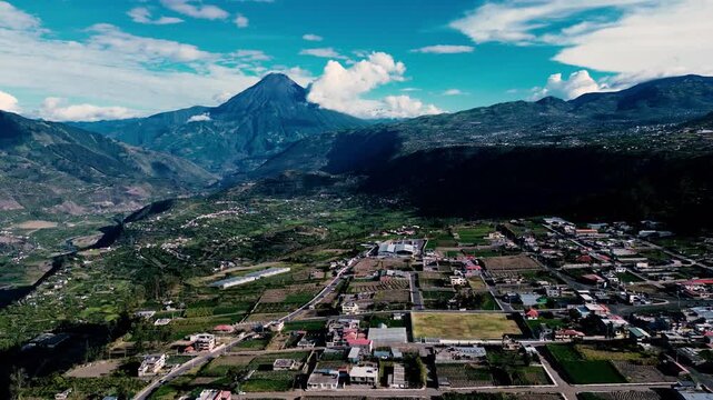 Drone footage overlooks a patchwork of green and brown fields across a rural hillside in Tungurahua, Ecuador. Winding roads connect scattered homes and small settlements among cultivated land, trees a