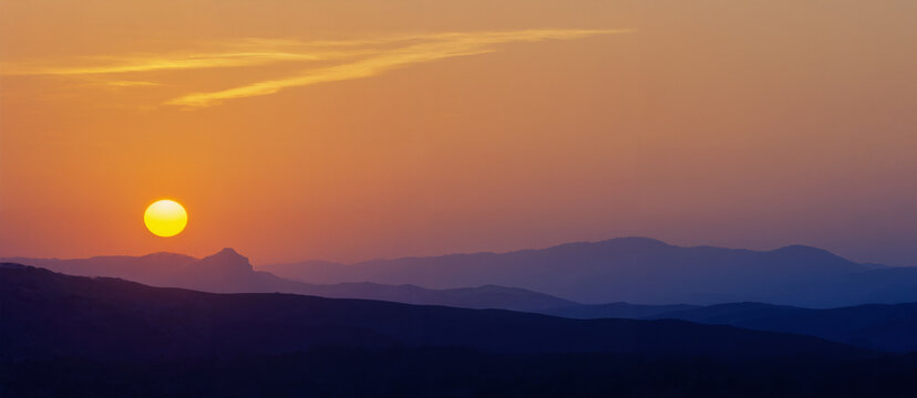 Tramonto sulle montagne con sole arancione