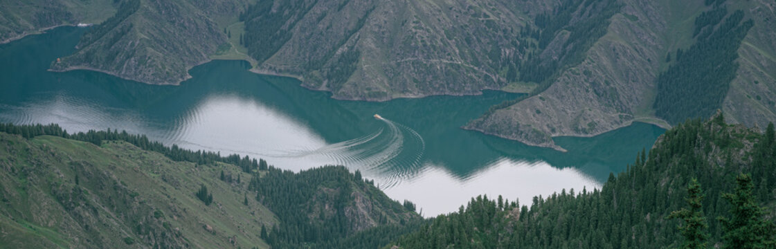 Boat Wake on Turquoise Mountain Lake Surrounded by Forested Hills