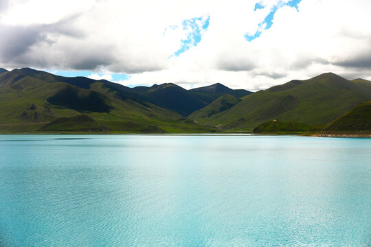 Turquoise Mountain Lake with Green Hills and Cloudy Sky