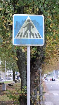 Weathered pedestrian crossing sign on a city street
