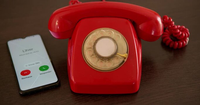 Past Meets Present Communication: A classic red rotary telephone sits beside a modern smartphone, symbolizing the evolution of communication technology.