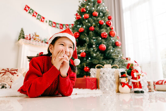 Excited Girl in Santa Hat Celebrating Christmas by Festive Tree